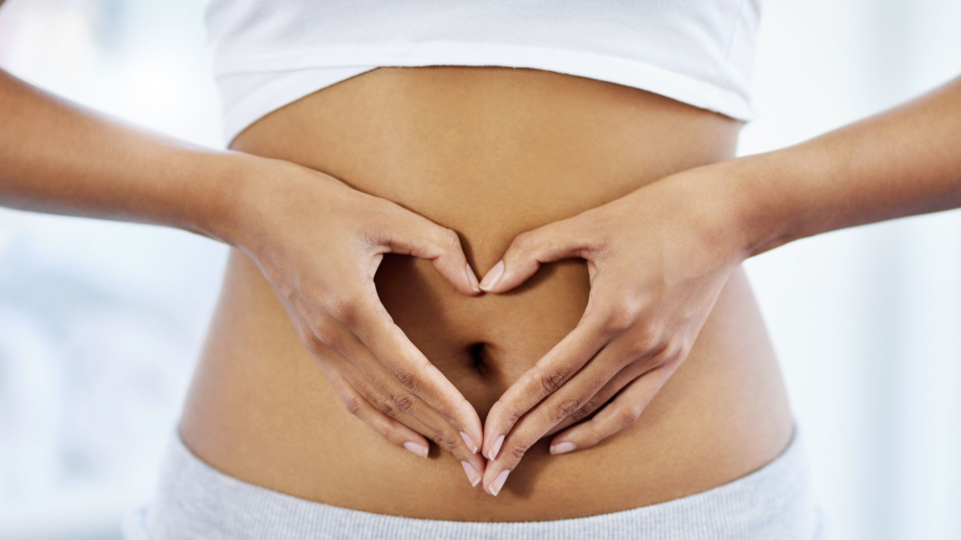 Woman making heart with hands on her stomach symbolising good gut health